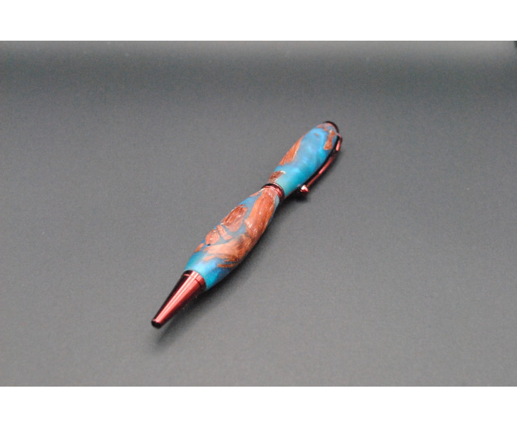 La imagen contiene boligrafo en madera de palo rojo y toques de resina epoxi azul.